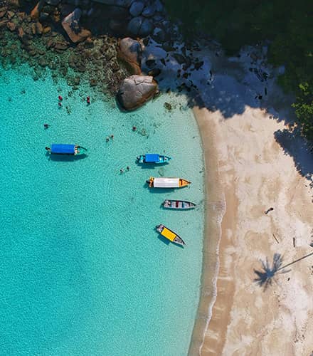 Sand beach, with turquoise water. 5 boats pulled up close to shore (certified professional career coach)